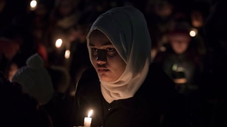 A young woman stands with people as they gather to observe a candlelight vigil for victims of the shooting at a Quebec City mosque. Quebec Shooting Vigils 20170130