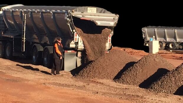Live bottom trailers allow for dumping without tilting the trailer. A live bottom trailer dumps out material as a worker keeps watch.