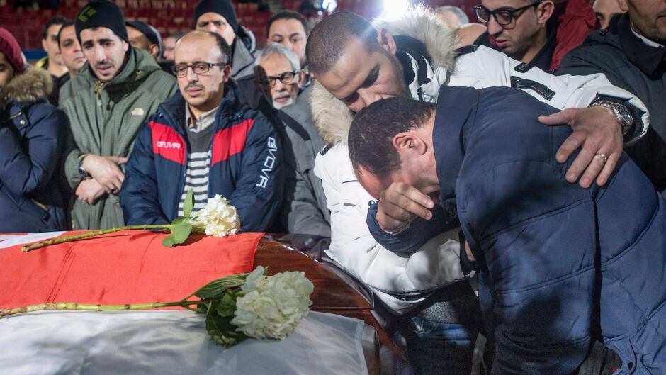 A man breaks down next to the caskets of three of the six victims of the Quebec City mosque shooting during funeral services at the Maurice Richard Arena Thursday, February 2, 2017 in Montreal.