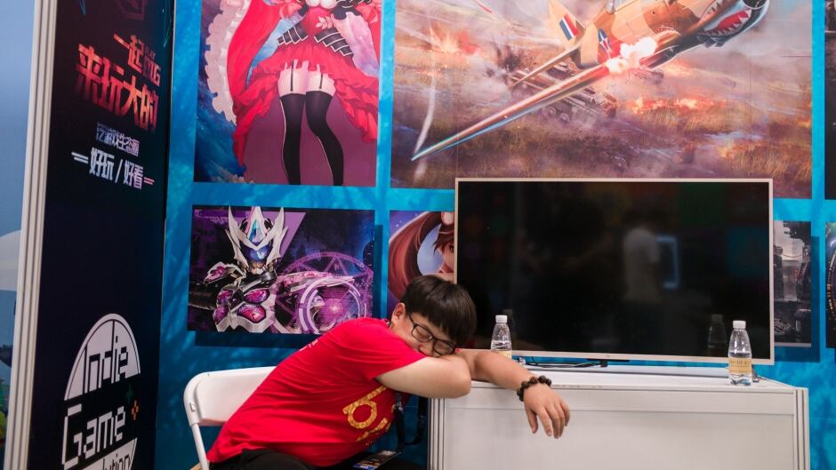 A man sleeps on his desk during the Beijing Comic convention in Beijing on June 10, 2016.