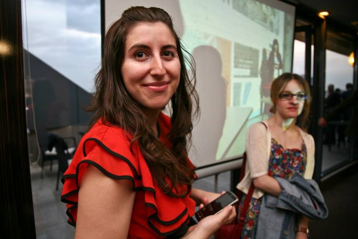 Woman in red and black shirt smiles at camera