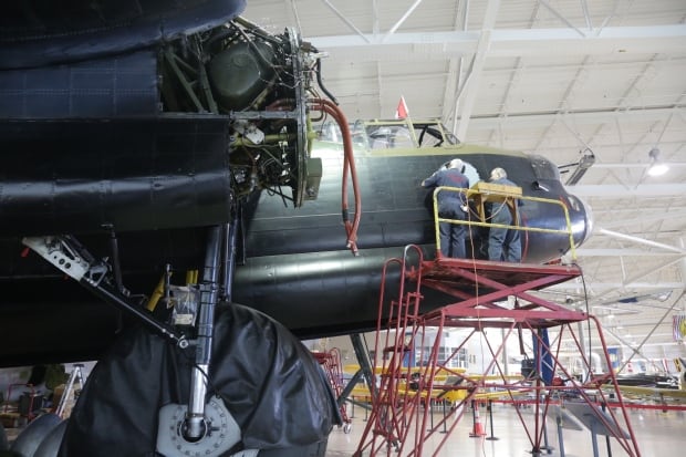 Workers remove an old decal from the Lancaster.