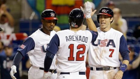 United States' Adam Jones, left, and Christian Yelich (7) congratulate teammate Nolan Arenado (12) after hitting a three-run home run against Canada on Sunday. WBC Canada US Baseball