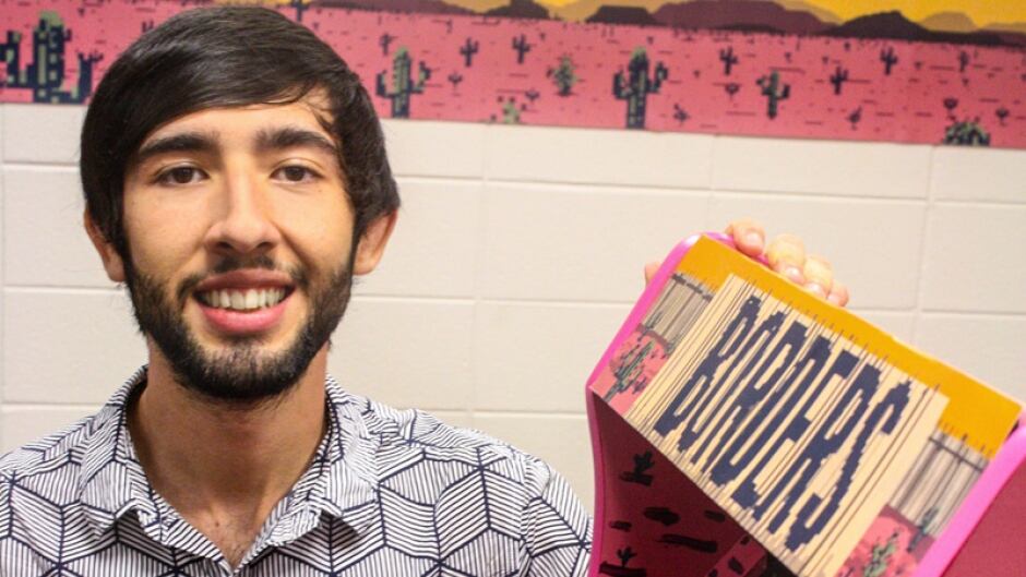 Gonzalo Alvarez poses next to a arcade-style installation of his video game Borders, which he created with the help of Jon DiGiacomo and Genaro Vallejo Reyes.