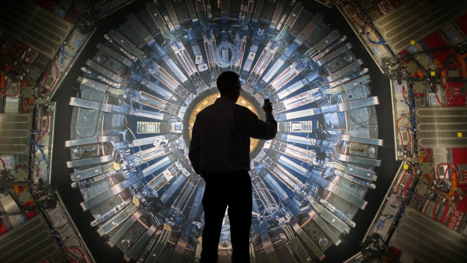A visitor takes a phone photograph of a large back lit image of the Large Hadron Collider (LHC) at the Science Museum's 'Collider' exhibition in London, England in 2013. It touches on the discovery of the Higgs boson, or God particle, the realisation of scientist Peter Higgs' theory.