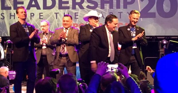 Flanked by PC caucus members, new party leader Jason Kenney waves to the crowd
