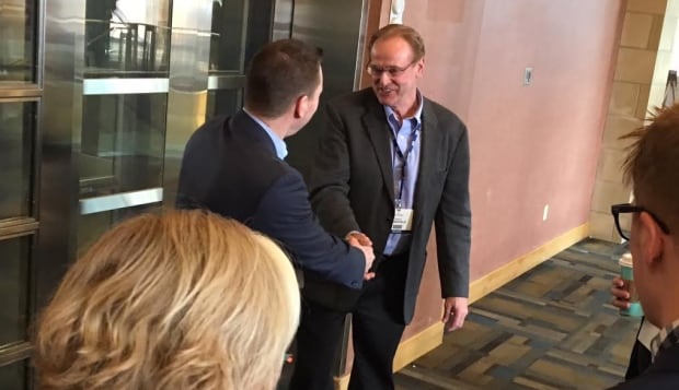 Economic Development Minister Deron Bilous shakes hands with former MP Rob Merrifield