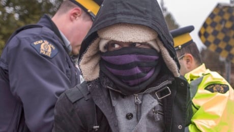 A man is frisked by RCMP officers as he is arrested for crossing the border from New York into Canada on Wednesday, March 8, 2017 in Hemmingford, Que. Refugees Border 20170308