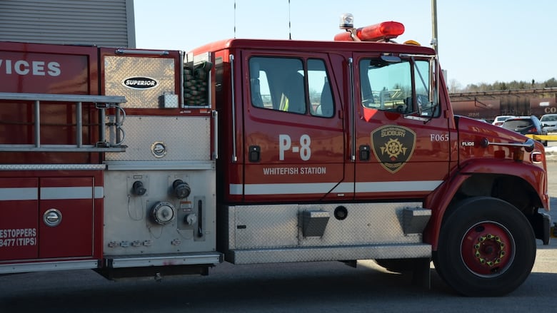 A red fire truck with the words "whitefish station" on it pulls out of a fire hall