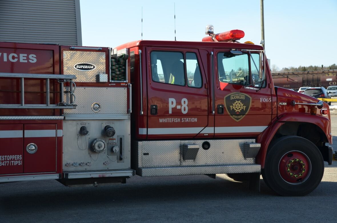 A red fire truck with the words "whitefish station" on it pulls out of a fire hall