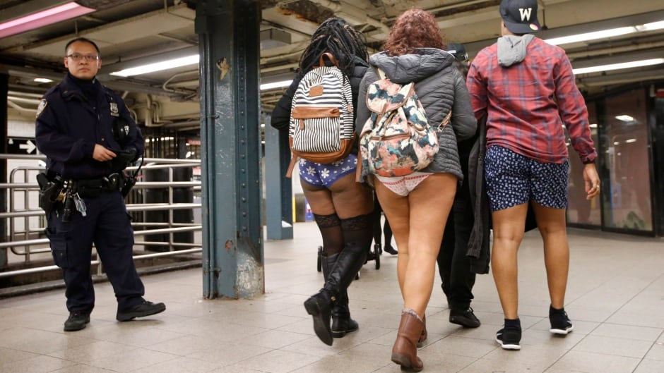 A police officer stands guard in a Manhattan subway station as three pantless people stroll by during the 15th annual No Pants Subway Ride, Sunday, Jan. 10, 2016, in New York. The group prank, meant to amuse, has been going on since 2002. (AP Photo/Kathy Willens)