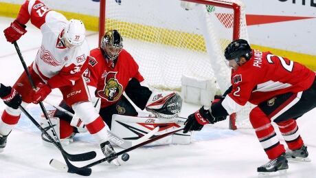 Ottawa Senators' Dion Phaneuf (2) reaches for the puck as Detroit Red Wings' Evegeny Svechnikov (37) looks on along with Senators goalie Craig Anderson (41) during first period. red-wings-senators