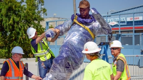 In this April 10, 2017, photo provided by the Los Angeles Dodgers, workers install a bronze statue of Dodgers legend Jackie Robinson outside Dodger Stadium in Los Angeles. Dodgers Robinson Statue Baseball