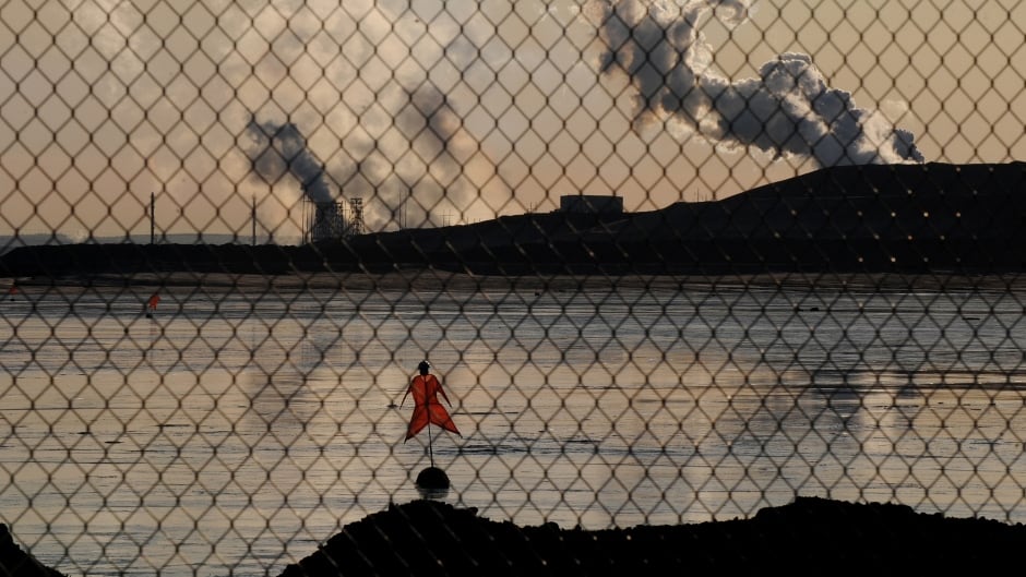 A scarecrow lies in a tailings pond in front of the Suncor oil sands extraction facility near the town of Fort McMurray in Alberta.