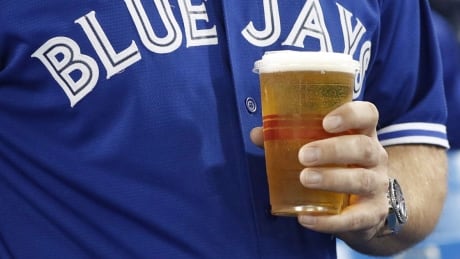 A man holds a beer in a plastic cup before the Toronto Blue Jays play the Texas Rangers play in American League Division Series action in Toronto on Sunday, October 9, 2016. Beer is being sold in cups instead of cans, after a fan threw a can of beer on the field that nearly hit a player in the American League wild-card game between the Toronto Blue Jays and the Baltimore Orioles. THE CANADIAN PRESS/Mark Blinch blue-jays-fan-beer