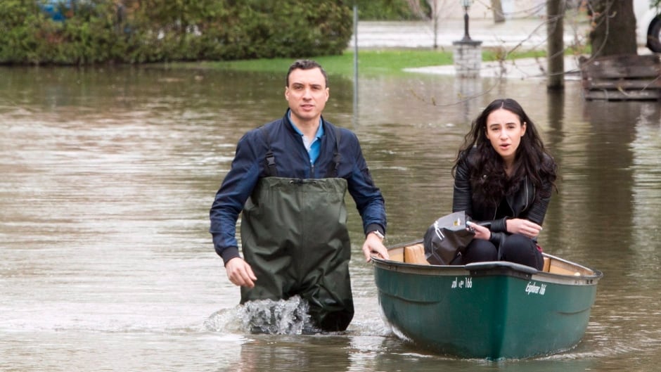 Residents make their way through a flooded streets in Laval, Que.