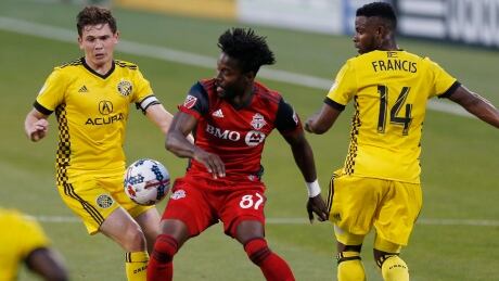 Toronto FC's Tosaint Ricketts, centre, tries to dribble the ball between Columbus Crew's Zack Steffen, left, and Waylon Francis during the first half. toronto-columbus