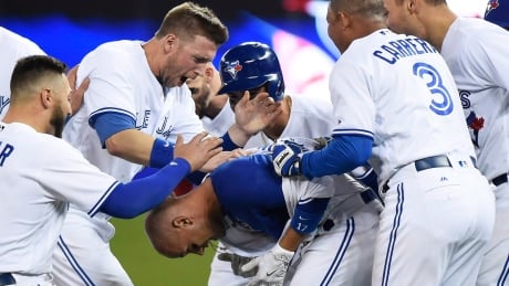 Toronto Blue Jays second baseman Ryan Goins, centre, celebrates with teammates after hitting a game-winning RBI single against the Cleveland Indians on Wednesday. goins