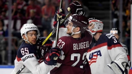 Teodors Blugers of Latvia, centre, and Danny Dekeyser, left, of the U.S. vie for the puck during World Championship ice hockey action on Saturday. Latvia-US-13052017