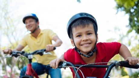 Kid riding bicycle with parent