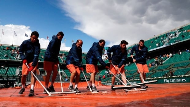 French Open staff worked to clear the rain from the court to no avail as the men's quarter-finals have been postponed until Wednesday. The women's matches have each been suspended in progress twice