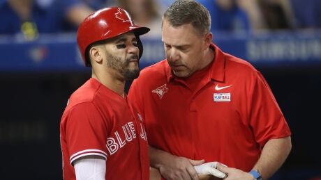 Devon Travis is tended to by trainer Mike Frostrad after being hit on the hand in Sunday's game against New York. A knee injury now has the second baseman on the DL. 96110316