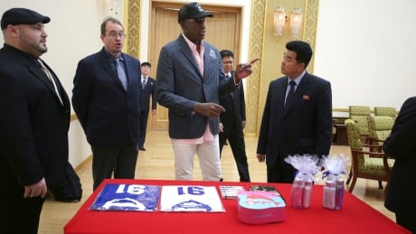 Former NBA basketball star Dennis Rodman presents gifts comprising of autographed basketball jerseys, bath soaps and two books, titled "Where's Waldo?" and "Trump The Art of the Deal" to North Korea's Sports Minister Kim Il Guk, right,on Thursday in Pyongyang, North Korea. Standing on his left is Joseph Terwilliger, Columbia University academic. North Korea Rodman