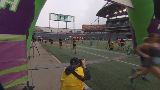 A runner celebrates as she crosses the finish line at Investors Group Field.