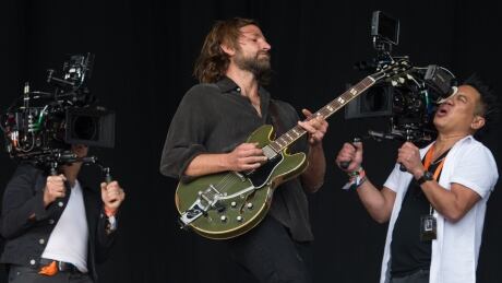 US actor Bradley Cooper plays a guitar as he is filmed for a re-make of the film 'A Star Is Born', on the Pyramid Stage at the Glastonbury Festival of Music and Performing Arts on Worthy Farm near the village of Pilton in Somerset, south-west England on June 23, 2017. AFP_PV218