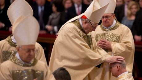 Cardinal George Pell poses his hands on the head of newly ordained bishop Peter Bryan Wells of the United States during a Mass for the ordination of Monsignor Peter Brian Wells and Monsignor Miguel Angel Ayuso Guixot, in St. Peter's Basilica at the Vatican, Saturday, March 19, 2016. Vatican Pope New Bishops