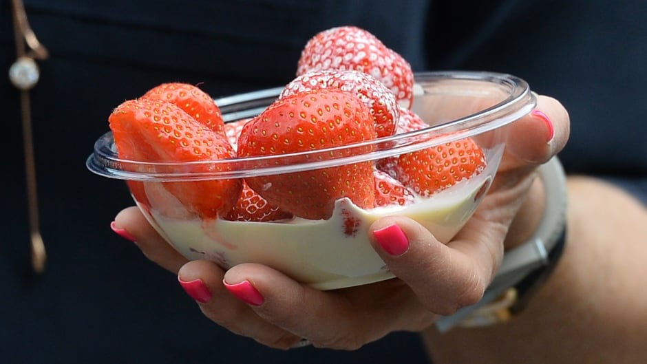 A spectator carries strawberries and cream on day three of the 2013 Wimbledon Championships tennis tournament at the All England Club in Wimbledon, southwest London.