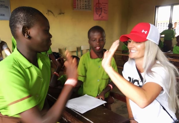 Kaylyn Kyle high-fiving student in Ghana
