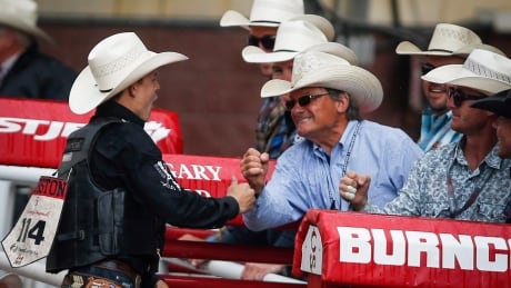 Zeke Thurston, left, of Big Vlley, Alta., celebrates winning the saddle bronc rodeo finals for the third year in a row at the Calgary Stampede. thurston-zeke