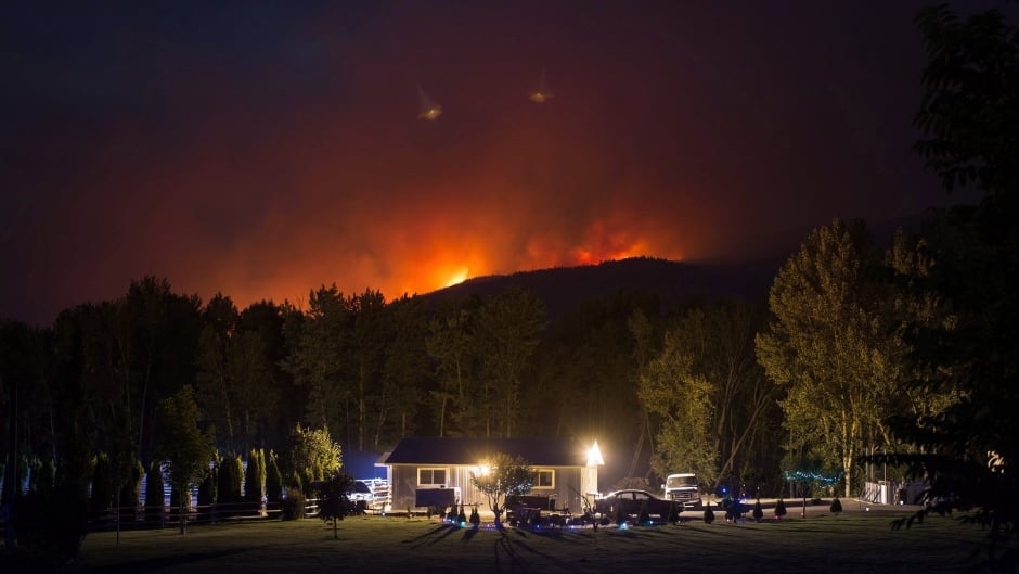 A wildfire burns on a mountain behind a home in Cache Creek, B.C., in the early morning hours of Saturday July 8, 2017.