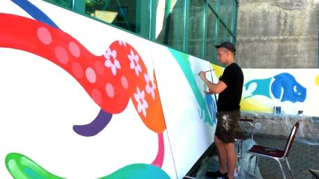 Kenneth Lavallee works on his portion of the 12-metre long mural going up at The Forks this week for the 2017 Canada Summer Games. Kenneth Lavallee