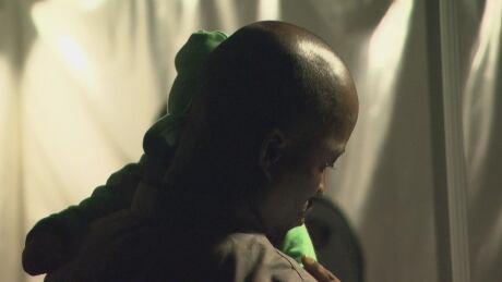 A man who crossed illegally into Canada holds the baby of a fellow traveller as they sort through their paperwork to show RCMP officers. Multiple pregnant women and families with newborns were amongst those who crossed from the United States into Canada on the night of August 1st. Refugees Border