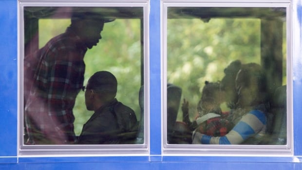 Asylum seekers board a bus after crossing the border into Canada from the U.S. at a police checkpoint close to the Canada-U.S. border near Hemmingford, Que., on Thursday.