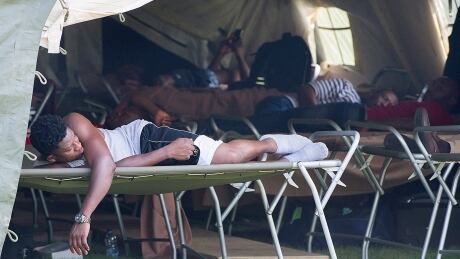 Asylum seekers rest in a tent at the Canada-United States border in Lacolle, Que. Que Asylum Seekers 20170810
