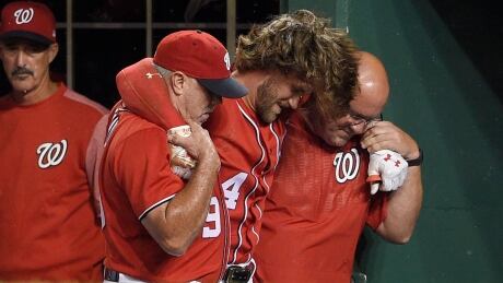 Washington Nationals' Bryce Harper is helped in the dugout after he was injured during the first inning. harper-bryce