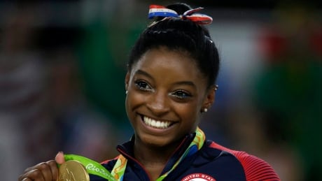American Simone Biles displays her gold medal for the floor routine during the artistic gymnastics women's apparatus final at the 2016 Games in Rio last summer. biles-simone-081616-620