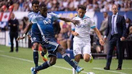 Vancouver Whitecaps midfielder Tony Tchani, left, fights for control of the ball with Seattle Sounders midfielder Cristian Roldan, right, during the second half of Wednesday's 1-1 draw. sounders-whitecaps