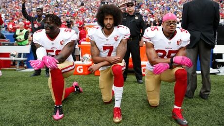 Eli Harold, Colin Kaepernick (centre) and Eric Reid of the San Francisco 49ers kneel in protest on the sideline during the national anthem at New Era Field on October 16, 2016. Kaepernick protest