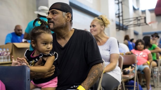 Caesar Mendez and his daughter Catalina wait inside the Corpus Christi Natatorium to board a bus to evacuate to San Antonio ahead of Hurricane Harvey on Thursday in Corpus Christi Texas