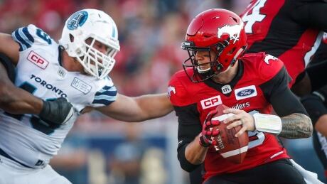 Toronto Argonauts' Jeffrey Finley, left, struggles to reach Calgary Stampeders' QB Bo Levi Mitchell during first half CFL action on Saturday. Argonauts-Stampeders-26082017