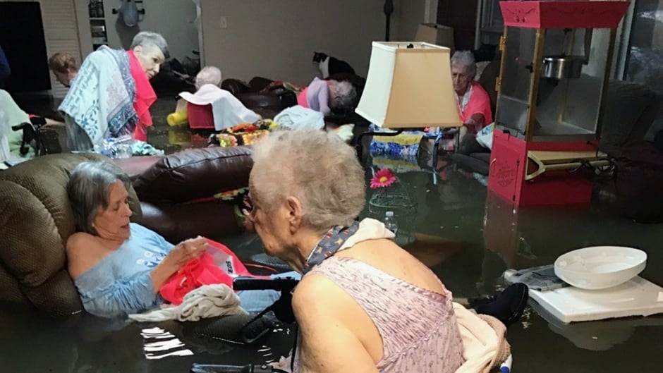 Residents of the La Vita Bella nursing home in Dickinson, Texas, sit in waist-deep flood waters caused by Hurricane Harvey on Sunday. Authorities said all the residents were safely evacuated from the facility. Trudy Lampson/Associated Press