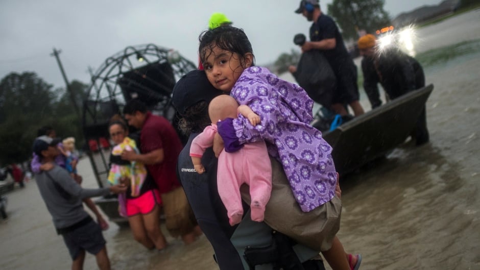 A woman holds a girl as her family arrives to high ground by boat due to floods in Houston. August 28, 2017.