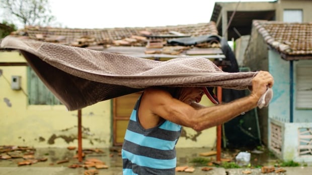 A man shelters himself against the rain after the passage of Hurricane Irma in Caibarien, Cuba on Saturday, Sept. 9, 2017.