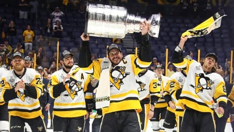 Sidney Crosby of the Pittsburgh Penguins hoists the Stanley Cup in celebration with teammates after defeating the Nashville Predators in Game 6 of the Stanley Cup playoffs. Pittsburgh-Penguins-11062017