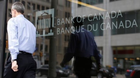 A man is reflected in a window while walking past the Bank of Canada office in Ottawa. CANADA-CENBANK/
