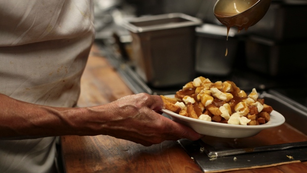 ​5 St. John's restaurants are shutting down. In a volatile industry, there's still hope; A close up of a hand holding a plate of poutine in a kitchen\.